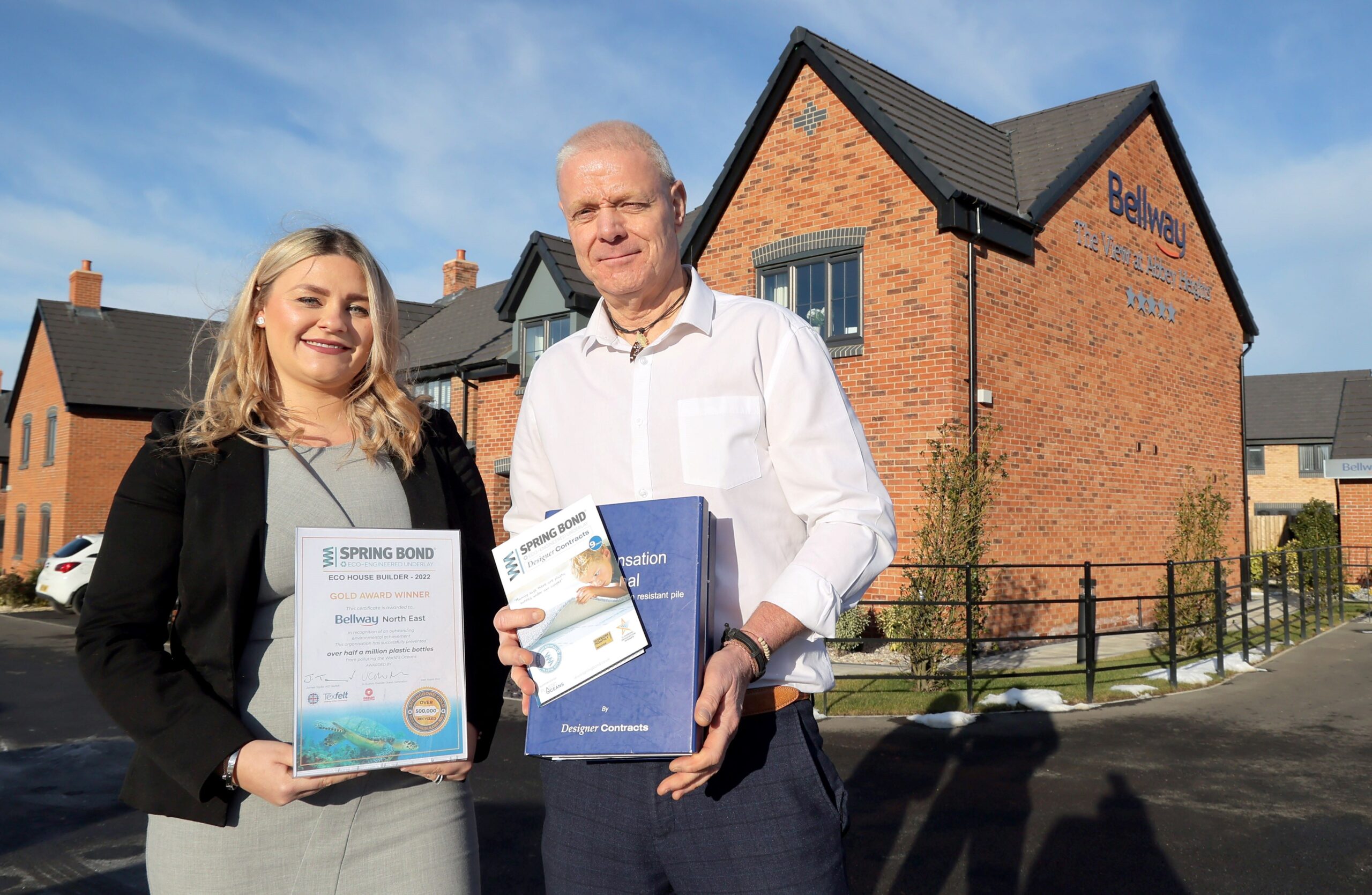 Barry Norton and Danielle Brown pictured in front of a Bellway home holding the Gold award