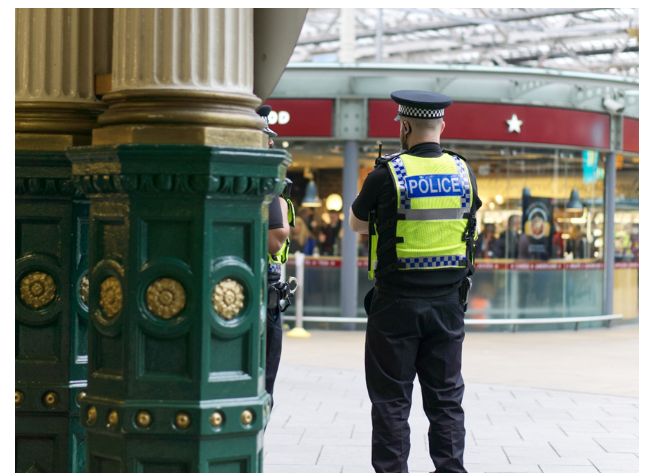 Police officers monitoring a busy London transport hub, illustrating visible policing and public safety measures in the city’s transport network.